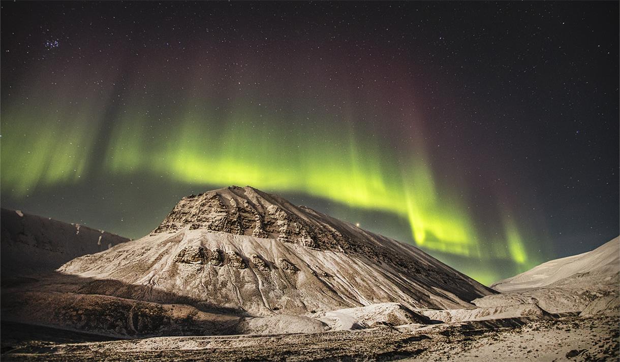 The aurora borealis glowing green over a snowy landscape